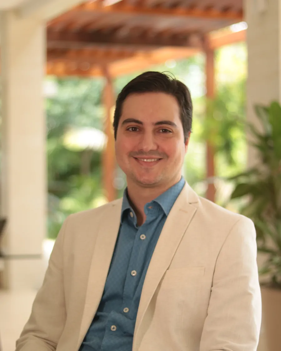 Dr. Diego Paiva sorrindo, sentado à mesa em ambiente claro