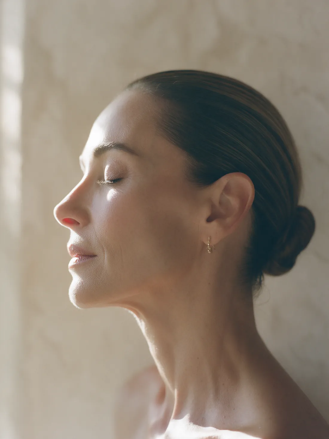 Perfil de mulher de olhos fechados, com luz dourada contornando o rosto